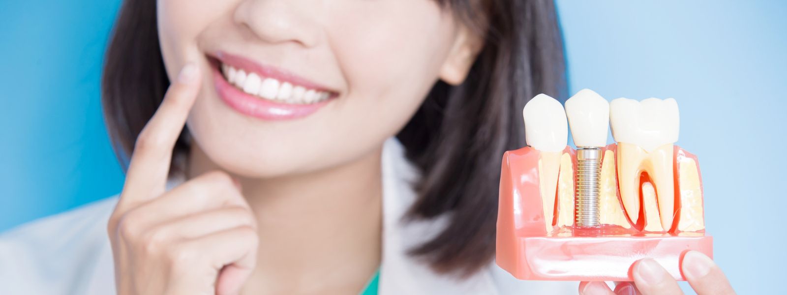 Girl wearing a white lab coat with dental implant model