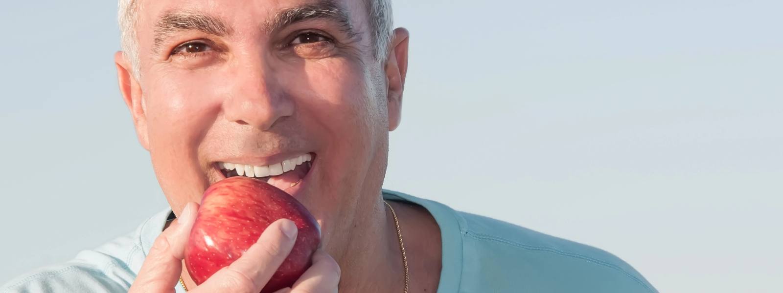 Happy senior person eating apple